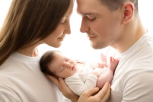 Parents with a baby in a newborn photography session.