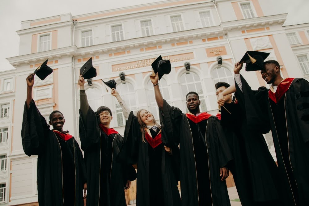 Group of graduates in gowns holding their caps.